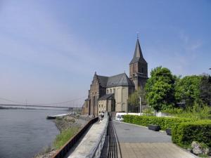 a church with a steeple on the side of a river at Modern appartement nabij boulevard in Emmerich