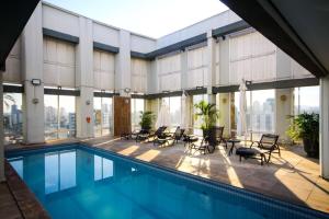 a building with a swimming pool and chairs at Flat Executivo GRU Airport in Guarulhos