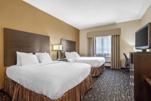 a hotel room with two beds and a flat screen tv at Best Western Plover-Stevens Point Hotel & Conference Center in Plover