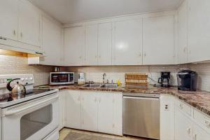a white kitchen with white cabinets and a sink at The CAVU Mansion on Bellevue in Oklahoma Heights +20 photos