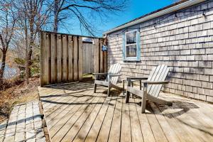 two chairs and a table on a wooden deck at Calm Waters in Bourne