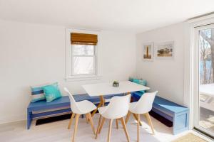 a dining room with a blue bench and white chairs at Calm Waters in Bourne