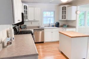 a kitchen with white cabinets and a wooden floor at Ravenswood Pool House in Sawyer +23 photos