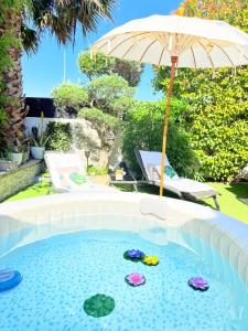 a pool with an umbrella and two turtles in it at O jardin des Sens -Séjour Bien-être & détente &Jacuzzi in Béziers