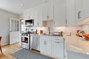 a white kitchen with white cabinets and a sink at Harbor Point Cottage in Bourne +19 photos