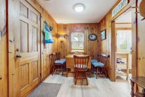 a dining room with wooden walls and a table and chairs at Uncle Rolfs Cozy Cottage in Dennis Port