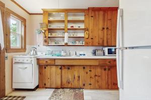 a kitchen with wooden cabinets and a sink and a refrigerator at Uncle Rolfs Cozy Cottage in Dennis Port
