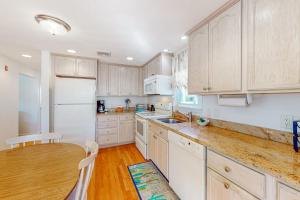 a kitchen with white cabinets and a wooden table at Cape Estate 6 in South Dennis