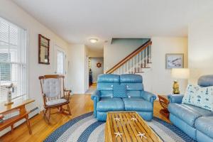 a living room with a blue couch and a chair at Wharf Side Hideout in Hyannis