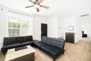 a living room with a black couch and a ceiling fan at Stay Awhile in Honor