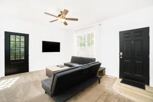 a living room with a black couch and a ceiling fan at Stay Awhile in Honor