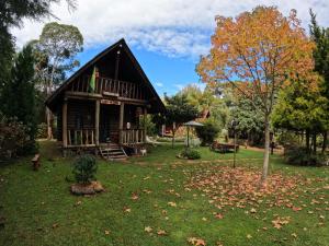 a log cabin in a yard with leaves on the grass at Chalé Cafofo in Campo Alegre