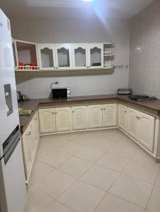 a kitchen with white cabinets and a white tile floor at Villa Familiale Exception in Saïdia