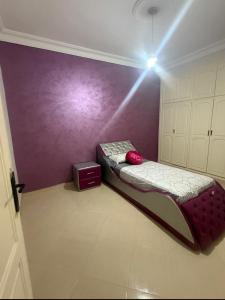 a bedroom with a bed and a purple wall at Villa Familiale Exception in Saïdia