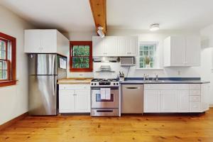 a kitchen with white cabinets and stainless steel appliances at Family Tides in Barnstable