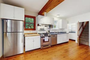 a kitchen with white cabinets and a stainless steel refrigerator at Family Tides in Barnstable