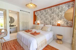 a bedroom with a white bed with a large painting on the wall at Studio Le Cosy Jungle & Piscine in Pointe-à-Pitre