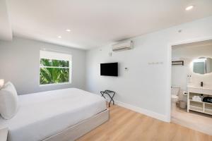 a white bedroom with a bed and a tv at Casa Collins in Miami Beach