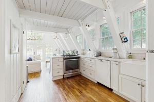 a large white kitchen with white cabinets and windows at Mt McSauba A Frame Cottage in Charlevoix +13 photos