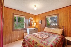 a bedroom with wooden walls and a bed and two windows at Walloon Lake Cottage in Boyne City