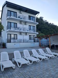 a row of white chairs in front of a building at Casa din Golful Dunării in Eşelniţa