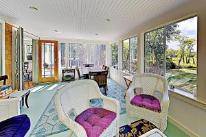 a room with chairs and a table and windows at Brookview Bungalow in South Wellfleet