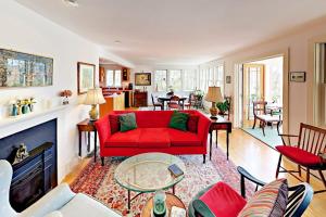 a living room with a red couch and a fireplace at Brookview Bungalow in South Wellfleet +22 photos