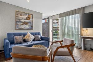 a living room with a blue couch and a chair at Cafe Hotel Medellín in Medellín