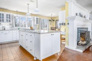 a kitchen with white cabinets and a fireplace at Birdie Bungalow in Saugatuck