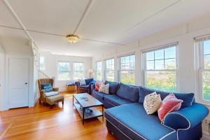 a living room with a blue couch and some windows at Bayview Bliss in West Yarmouth