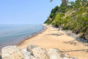 a beach with rocks and the water and trees at Appy Place in South Haven