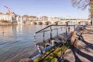 a bench next to a river with a bridge at Casa Rheinblick - Apartment C in Basel