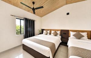two beds in a bedroom with a ceiling fan at Gir Wildtrack Lodge - Into the Deep Forest in Sasan Gir +54 photos