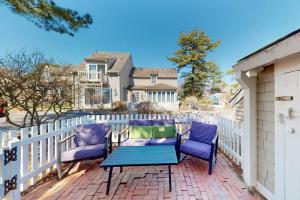 a patio with two chairs and a table and a fence at Maushop Village Beach Getaway in Mashpee