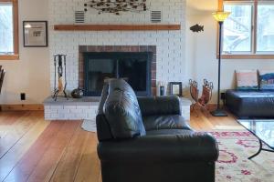 a living room with a leather couch and a fireplace at Hal-Sea-On House in Glen Arbor