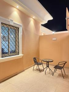 two chairs and a table in a room with a window at بستان الورد 2 in Taif