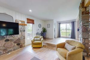 a living room with a stone fireplace with two chairs and a tv at Minutes from it All in Petoskey