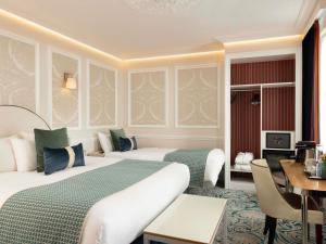 a hotel room with two beds and a desk at Hotel Mercure La Sorbonne Saint-Germain-des-Prés in Paris