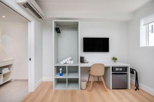 a white office with a desk and a tv on a wall at Casa Collins in Miami Beach
