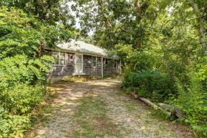 a house in the woods next to a dirt road at Escape in Dennis in Dennis