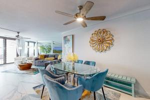 a living room with a ceiling fan and a glass table at Waves & Palms Oasis in Marco Island +37 photos