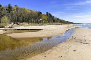 a sandy beach with trees and the water at 2nd Base in Sawyer