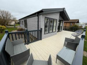 a deck with chairs and a small house at Luxury 3 bed lodge, Skegness - East Coast Holidays in Winthorpe