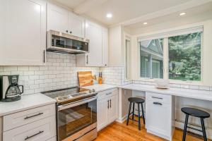 a kitchen with white cabinets and two bar stools at Birchwood: Meadows Bliss in Harbor Springs