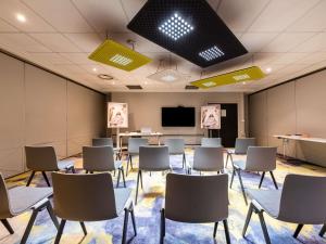 a conference room with chairs and a projection screen at Mercure Grenoble Meylan in Meylan