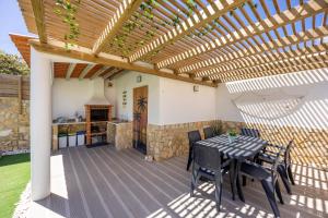 a patio with a table and chairs under a wooden pergola at SagresSeaHouse in Sagres