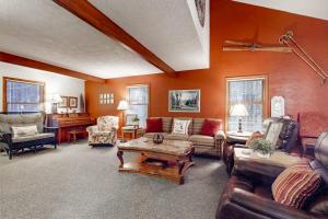 a living room with orange walls and couches and a piano at Crystal Mountain Retreat in Thompsonville