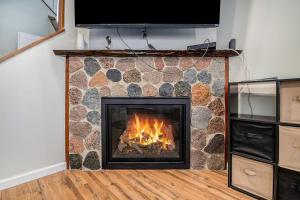 a fireplace with a stone wall and a television at Hideaway Valley Condo 36 in Harbor Springs