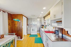 a kitchen with white cabinets and a wooden floor at Coastal Hideaway in Eastham