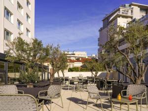 a patio with chairs and tables and trees and buildings at Mercure Marseille Centre Prado Vélodrome in Marseille